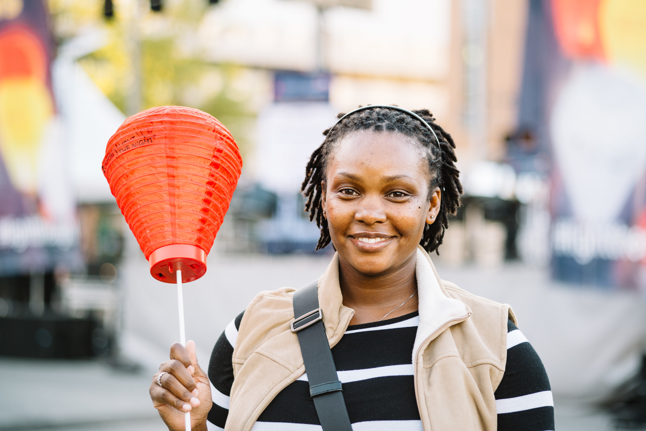 A woman holding out an unlit paper lantern during the day