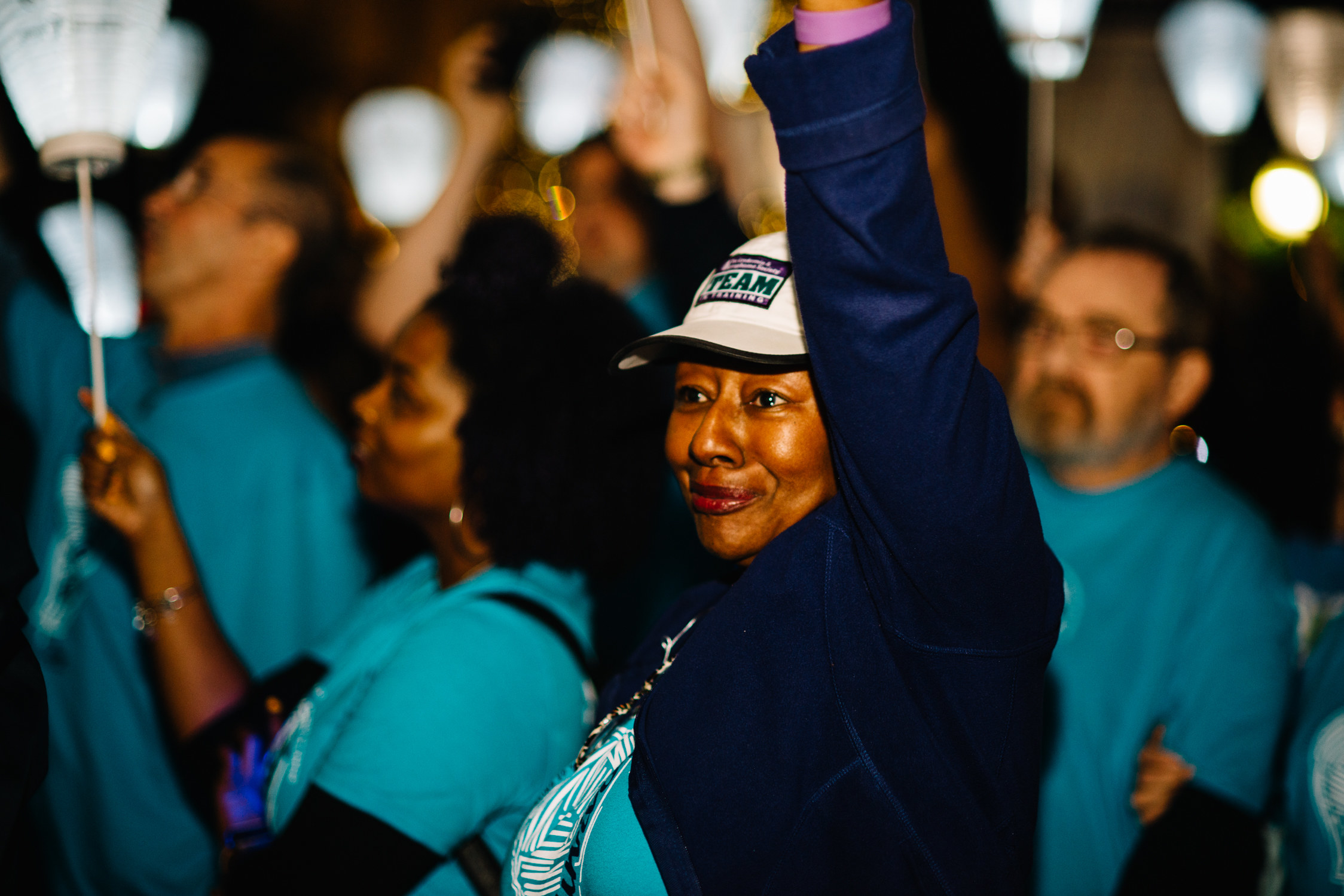 A woman standing in front of a crowd holding up lanterns, her eyes filled with emotion