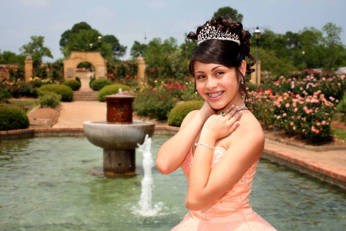 A girl all dressed up and smiling for a photo at her quinceañera