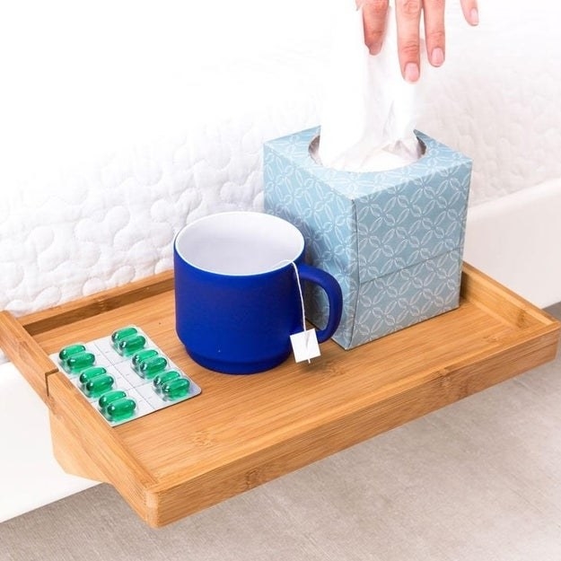 Close-up of the table, showing it holding a tissue box, mug and medicine