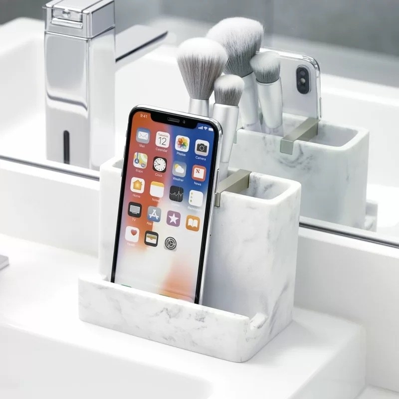 the sink caddy with a phone and brushes in it