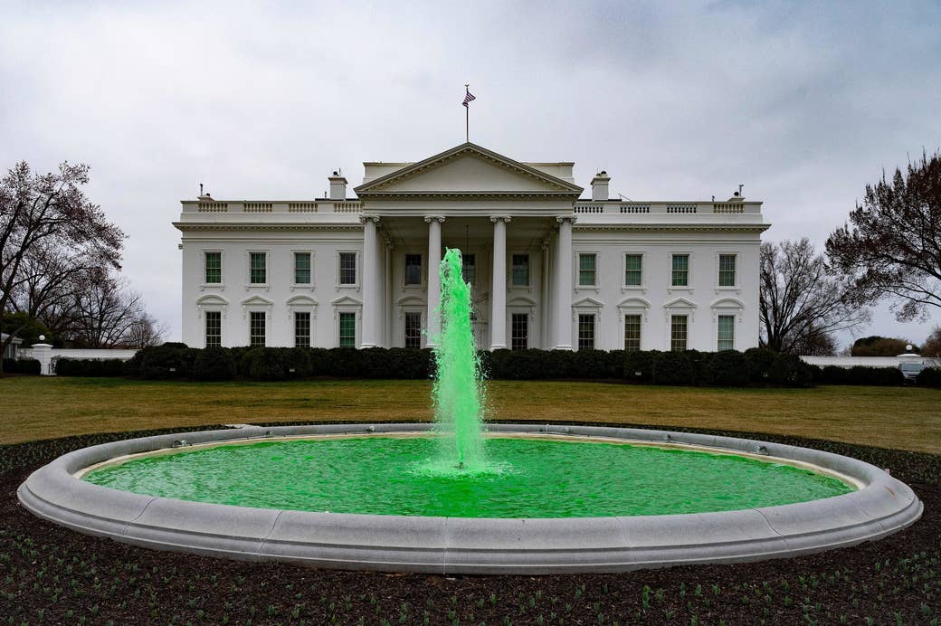 A view of the white house with a fountain in the foreground, the fountain is dyed green 
