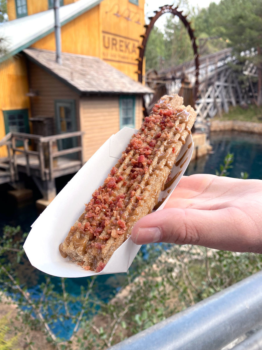 A churro with maple icing, and bacon bits on top