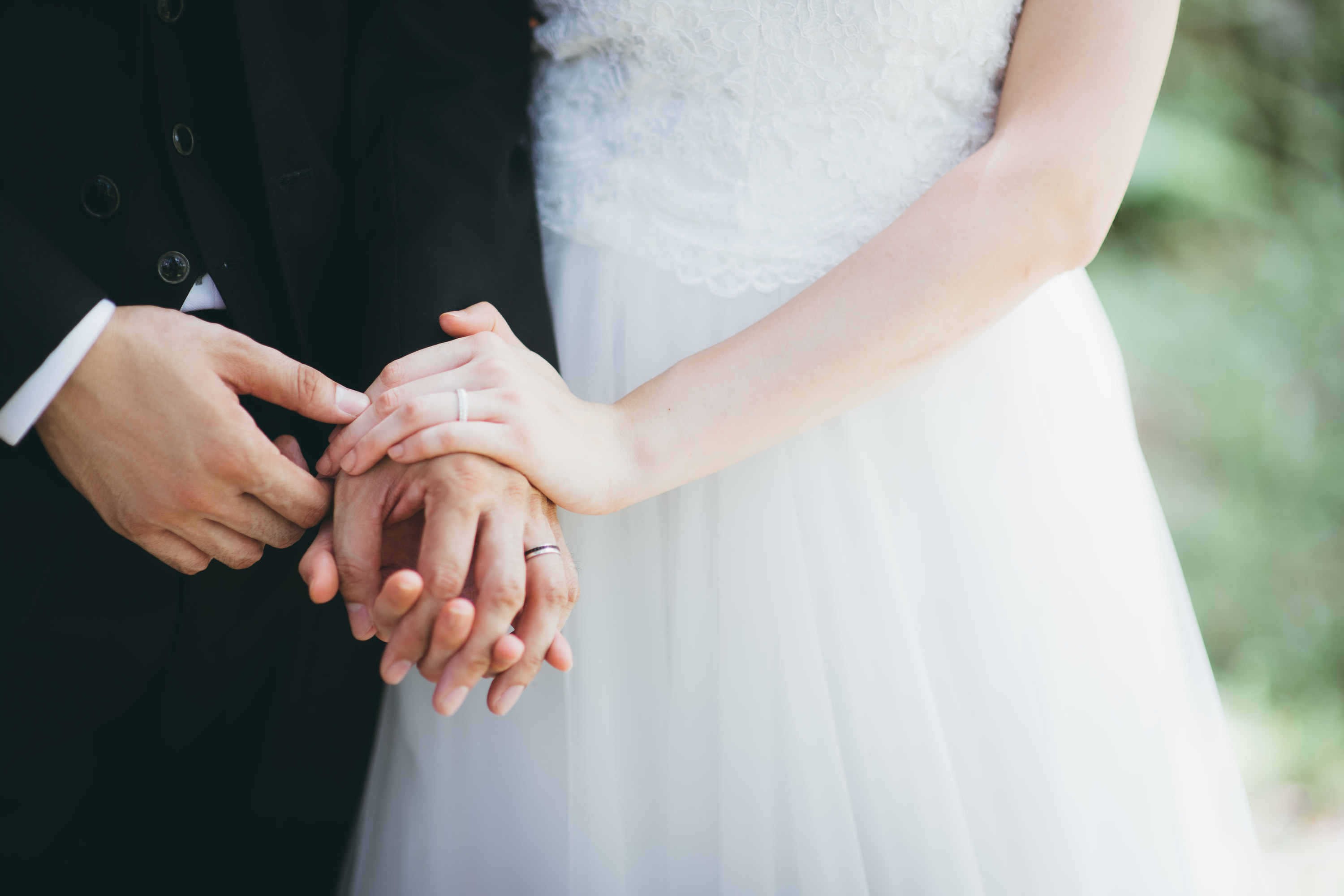 Close-up of a couple holding hands with wedding rings