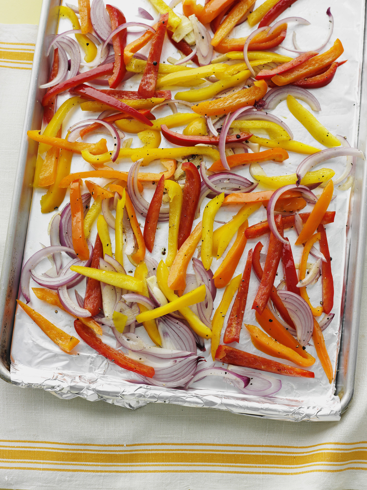 Onions and peppers on a foil lined sheet pan.