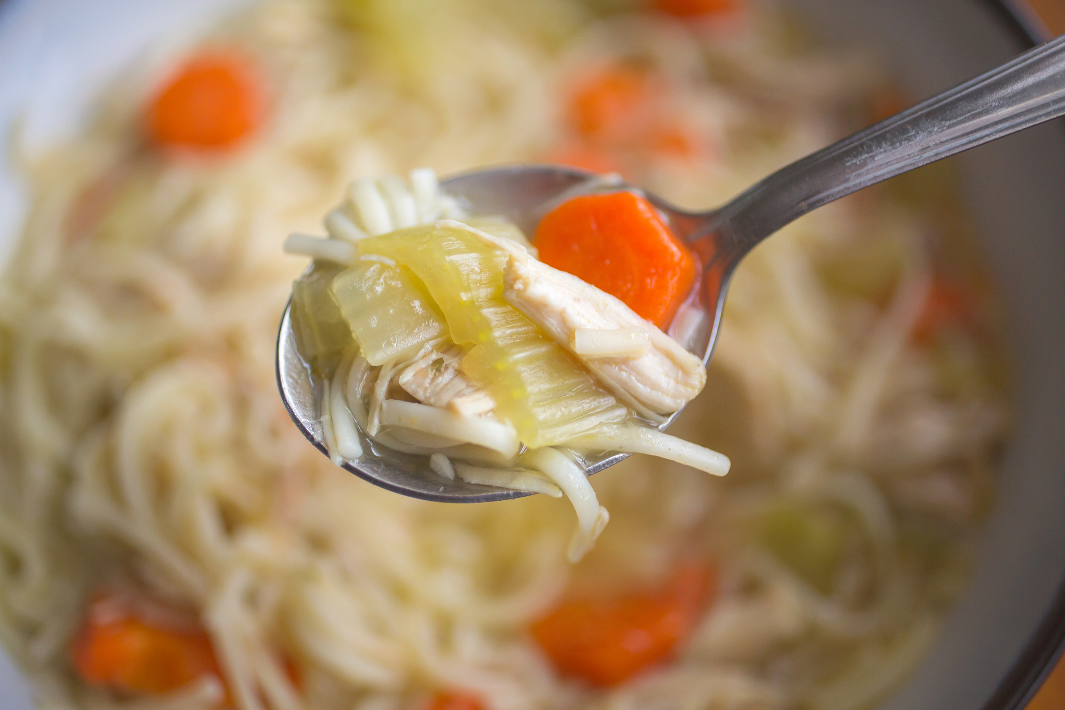 A spoonful of chicken soup with veggies.