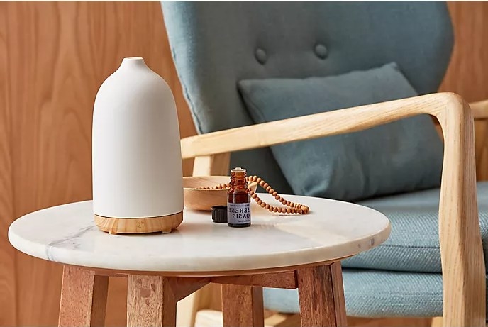 An image of a essential oil bottle on a table next to a diffuser