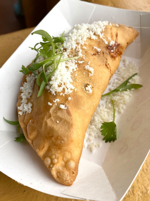 Close up of the empanada, which is a puff pastry covered in cotija cheese
