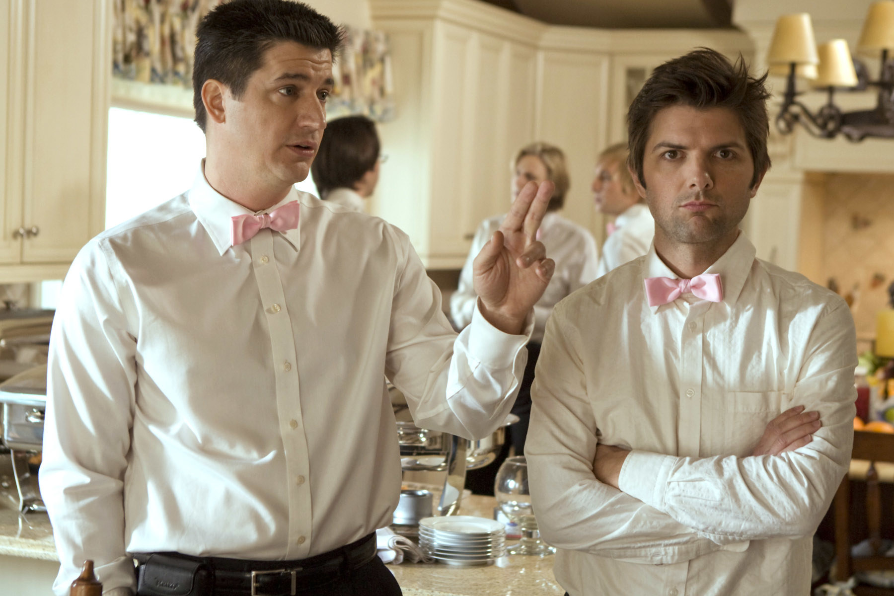 Kevin Marino and Adam Scott in whie button-downs and pink bow ties in a kitchen