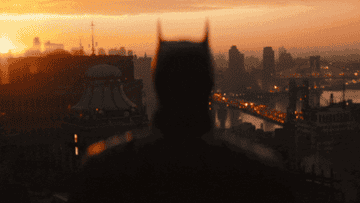 The Batman looking over Gotham as sunrise