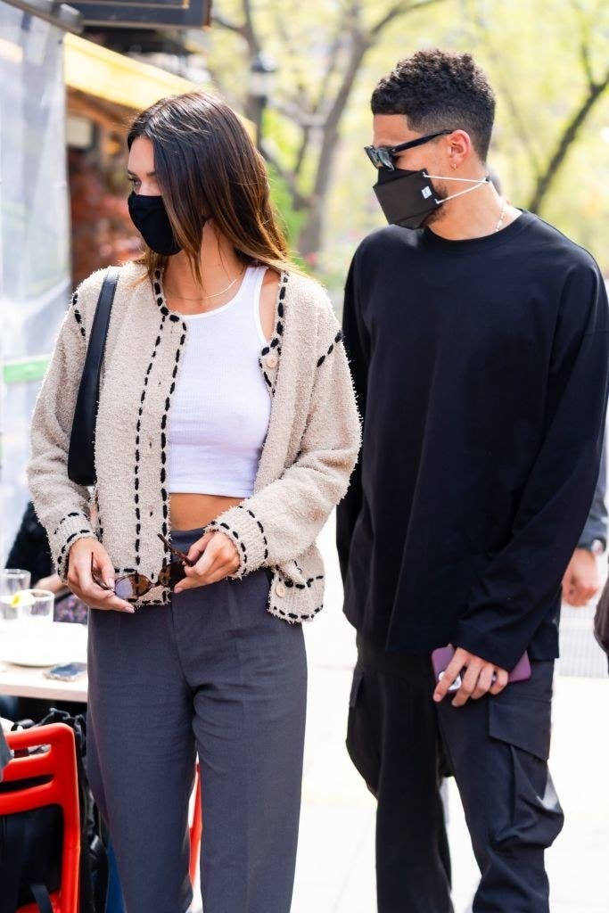both wearing masks and sweaters, the couple stands on the street together