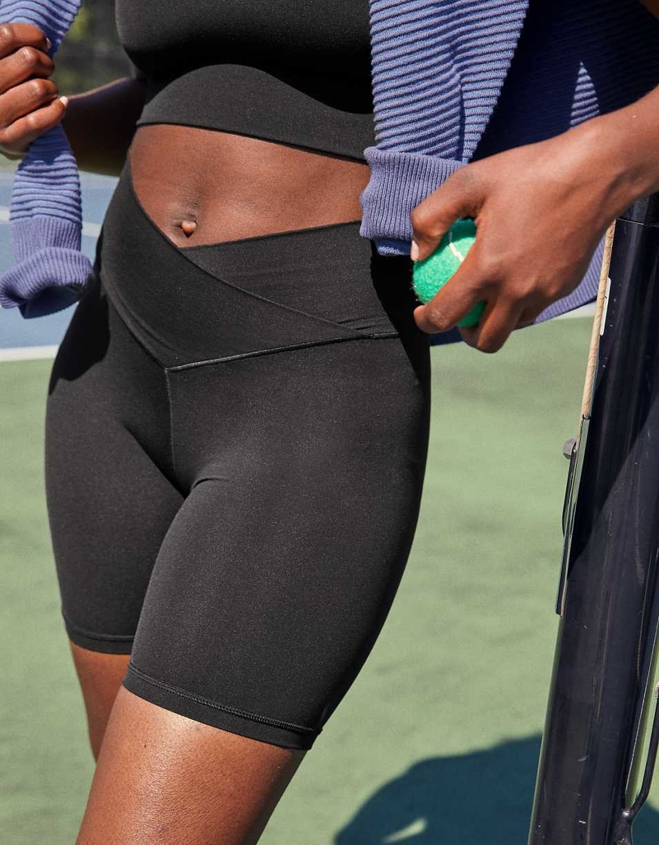 a model posing in black bike shorts with a crossover waist design