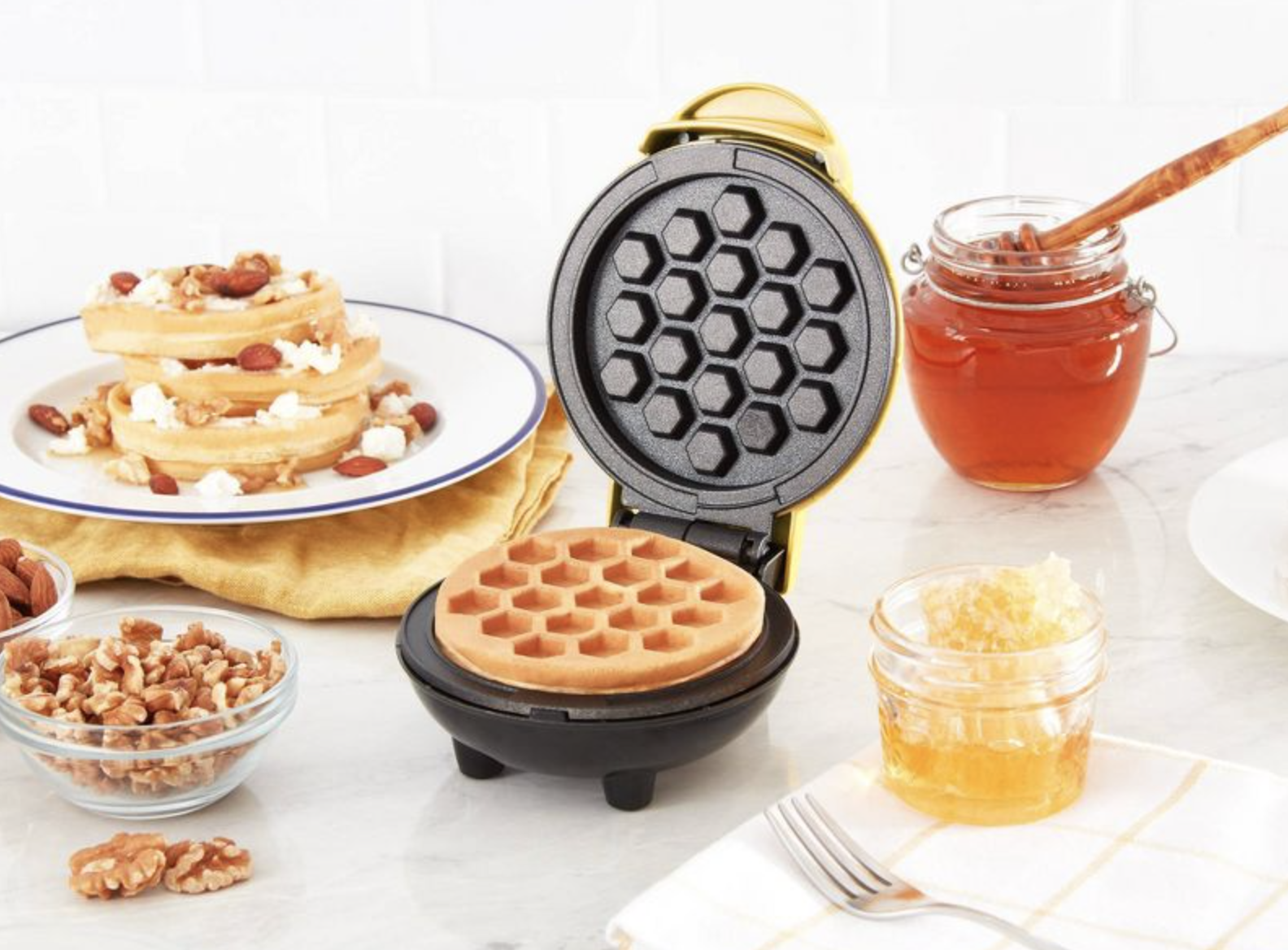 the waffle maker surrounded by honey and other waffles