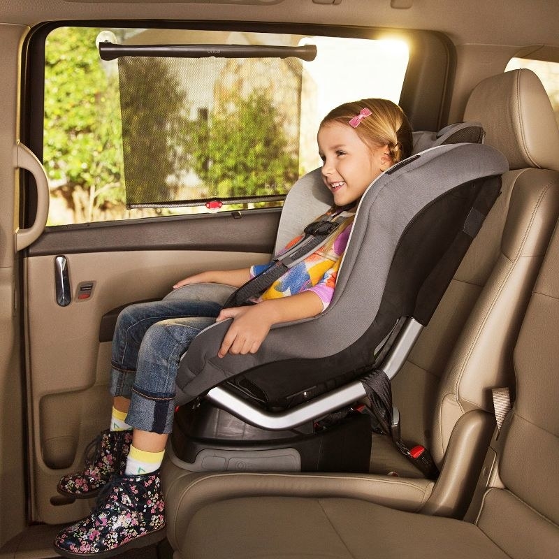 a child in a car seat next to a window with the shade