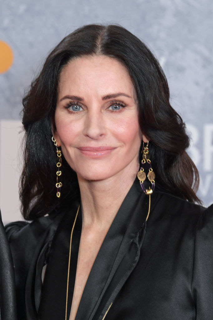 wearing a smart blazer and dangling gold earrings, Courteney smiles on the red carpet