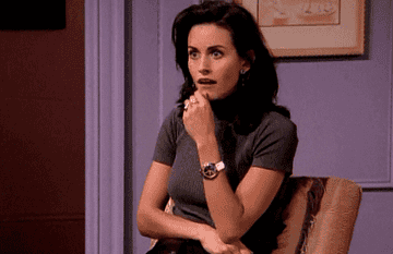 Monica gasps dramatically, covering her mouth with her hand