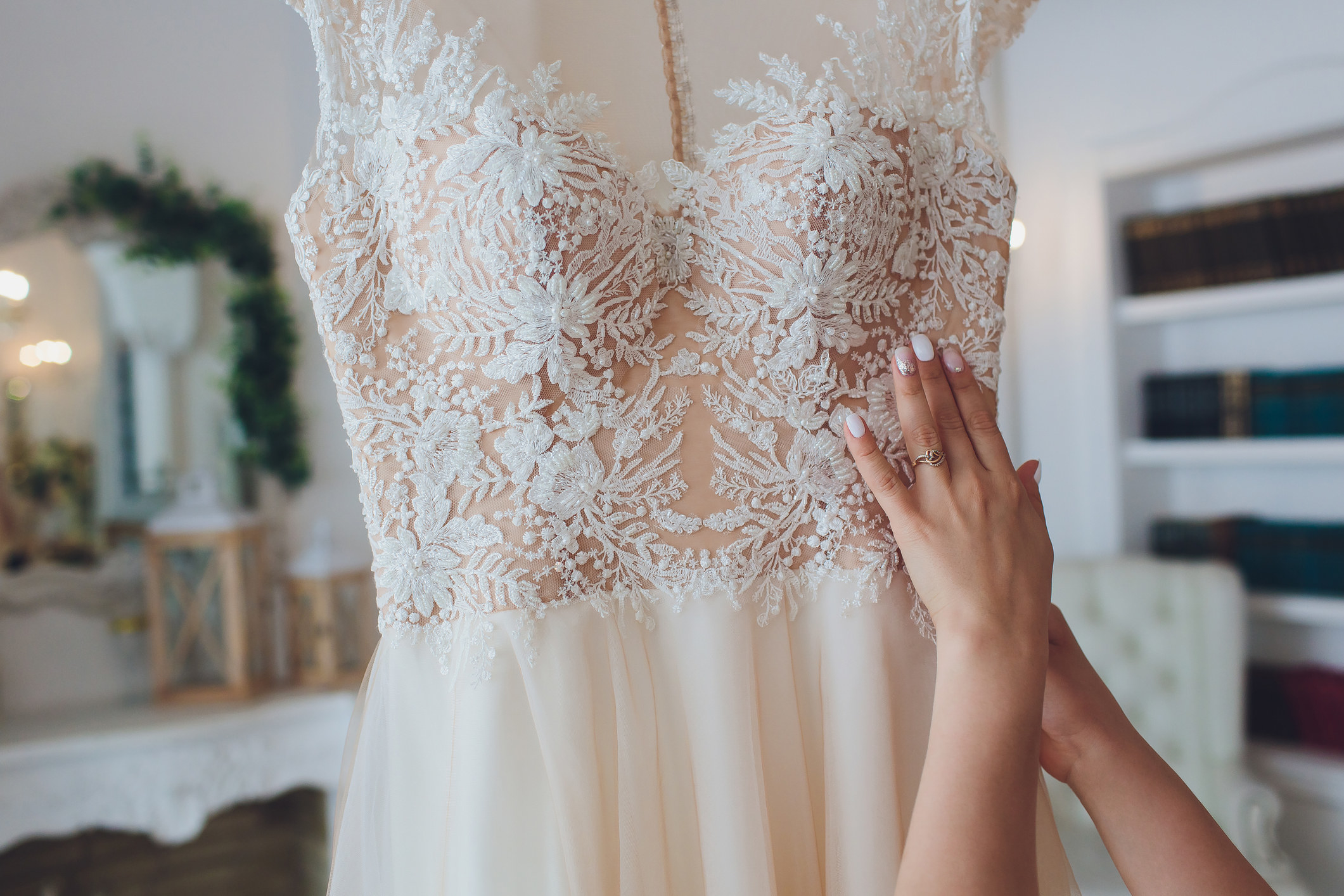 Hands touch a wedding dress hanging