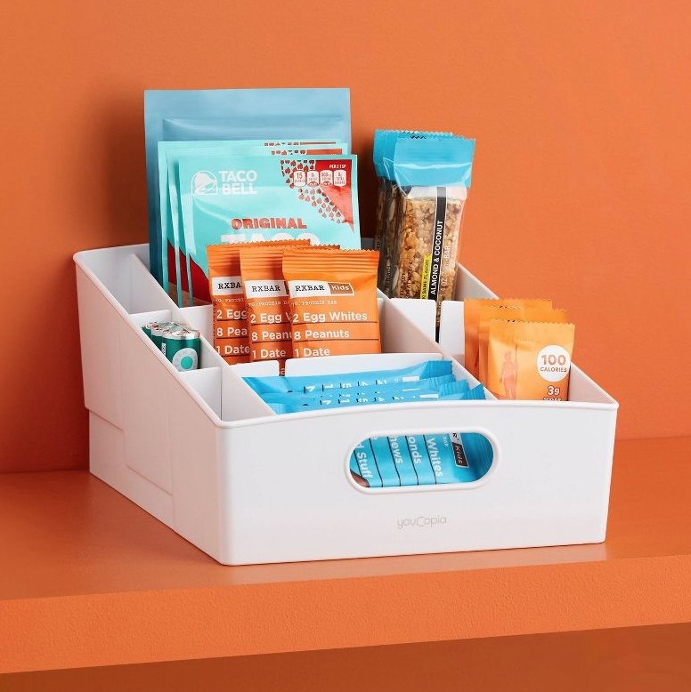 A shelf bin with 9 compartments filled with snack bars