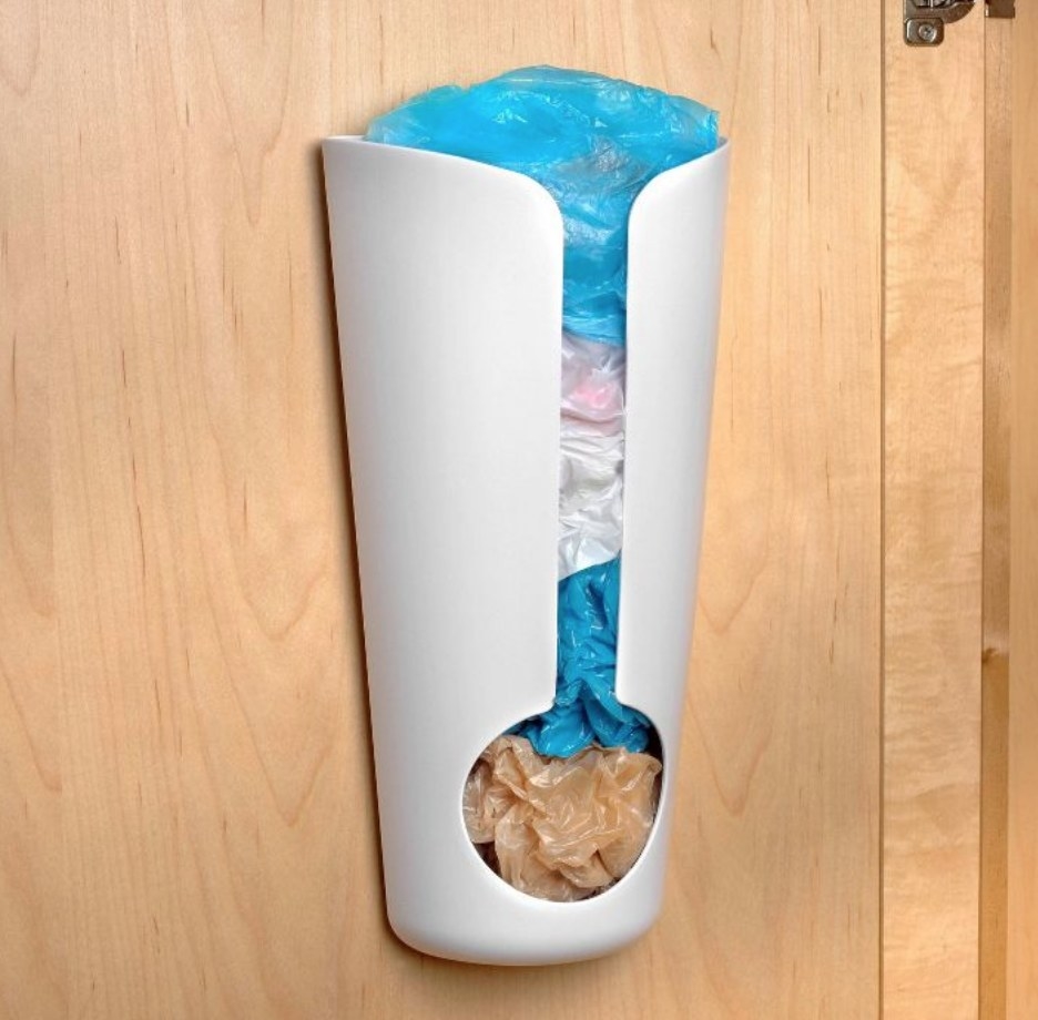 A white plastic bag holder mounted to the inside of a cabinet door