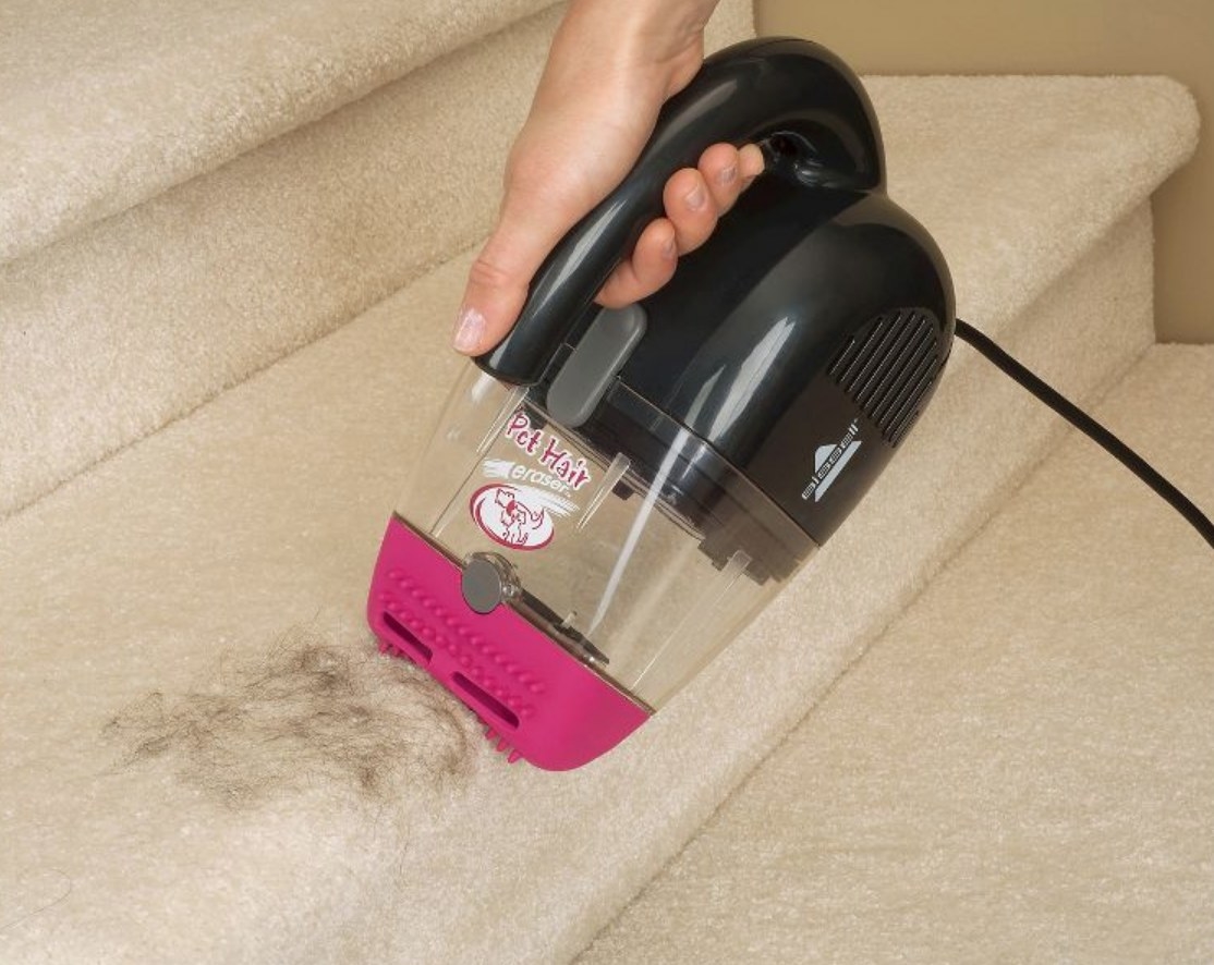 A model using a handheld pet hair erasing vacuum to remove hair from a staircase