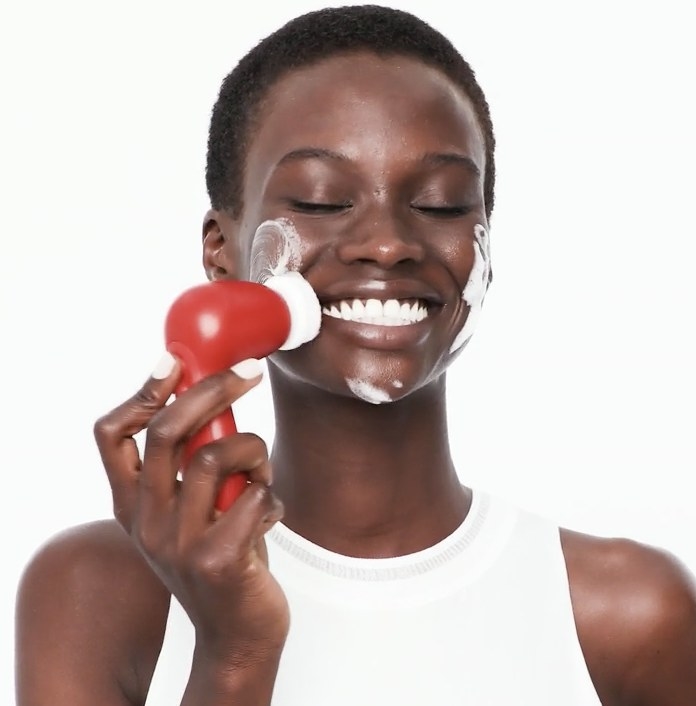 A model using a red facial cleansing brush
