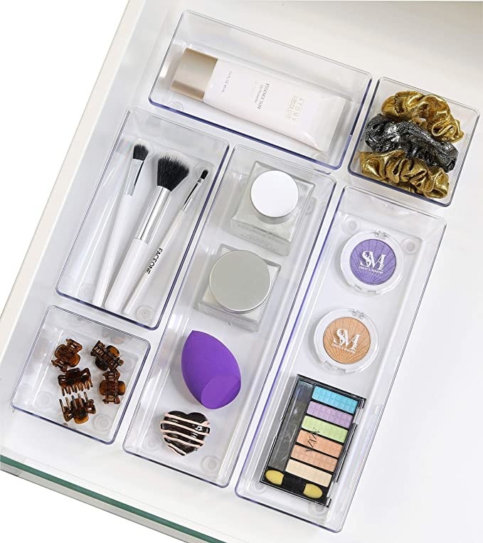 A set of clear organizers with different cosmetic items in it in a drawer