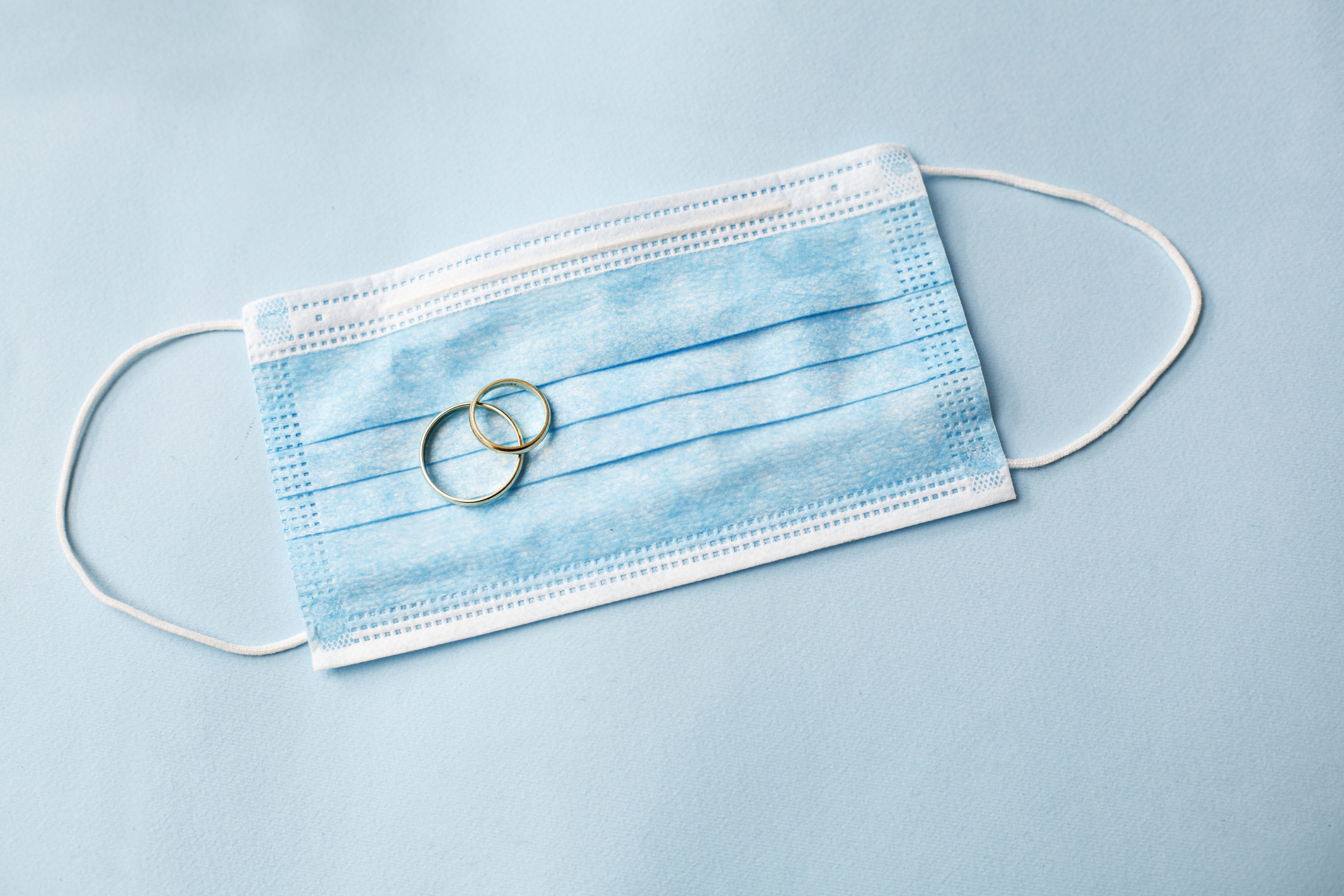 Two wedding rings on top of a surgical mask