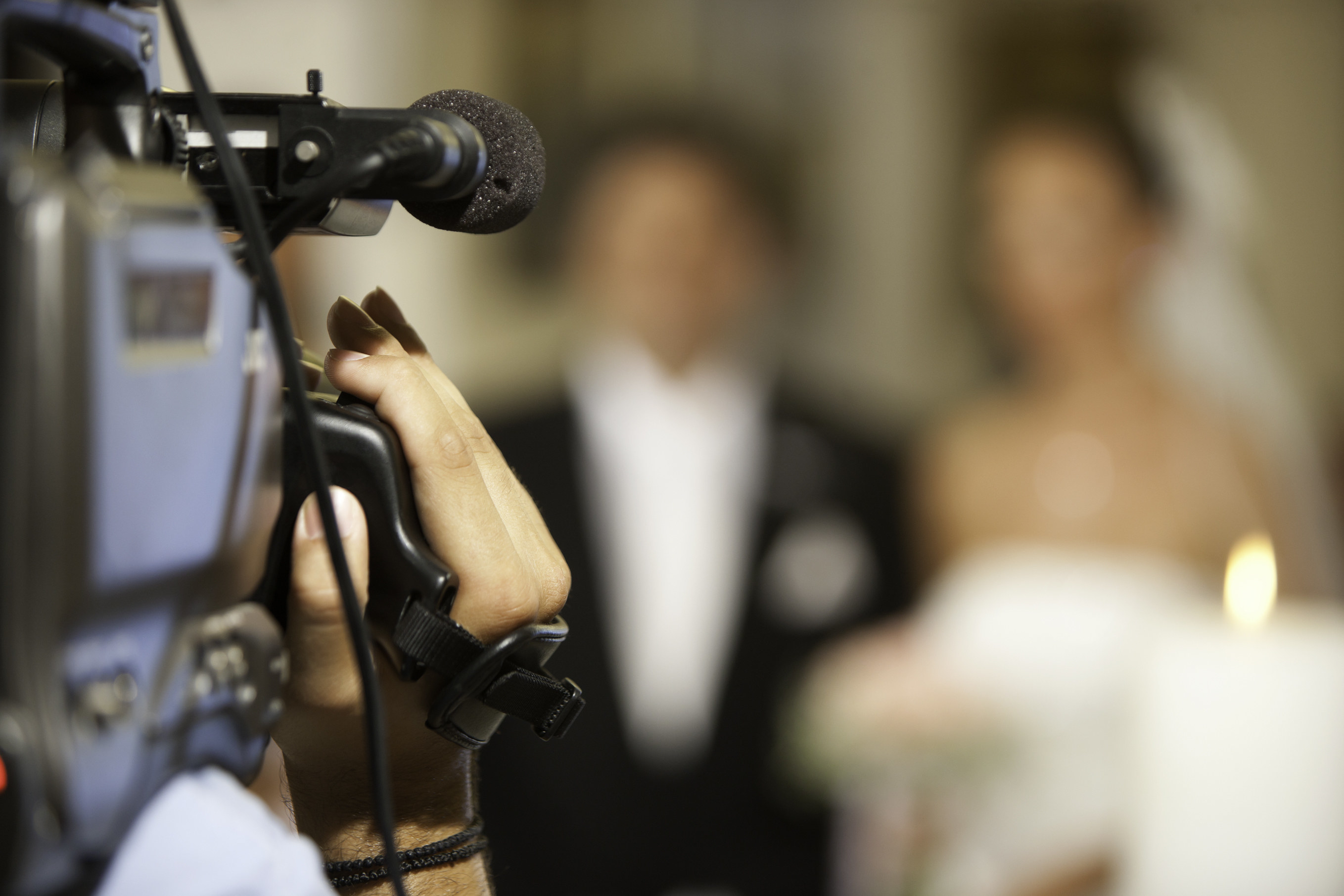 A video camera is pointed at a bride and groom