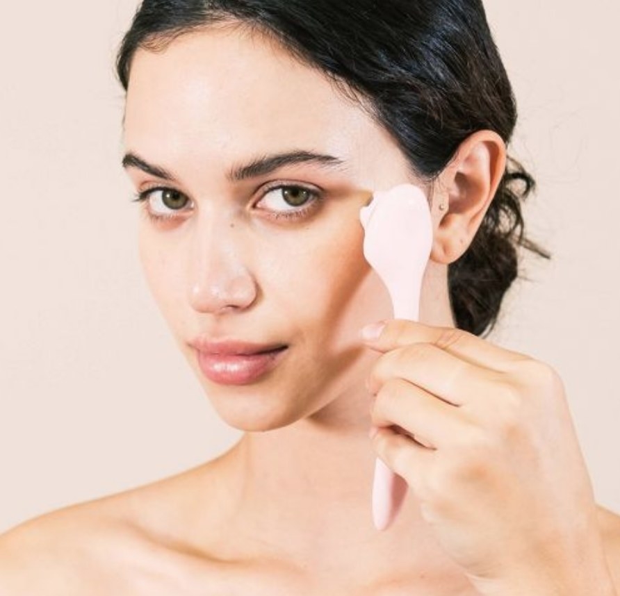 A model using a pink under eye massager