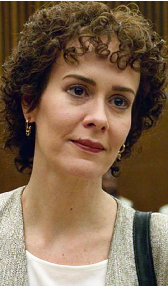 Paulson with short, curly hair in a courtroom