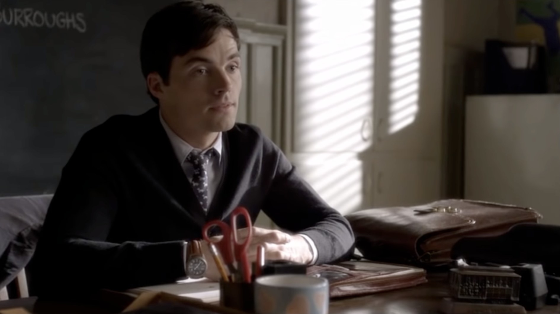 Ezra sitting at his classroom desk in Pretty Little Liars