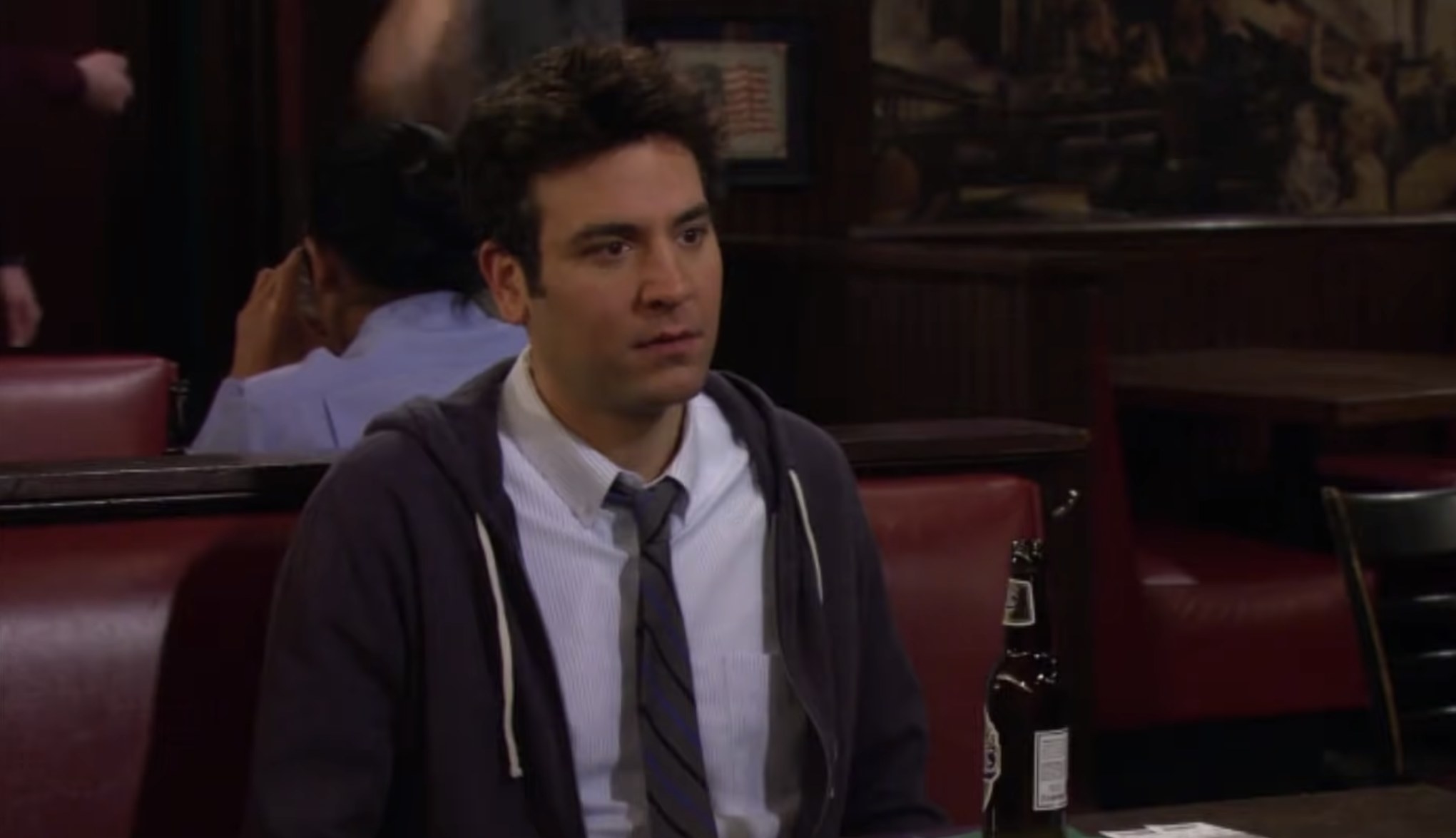 Ted sitting in a booth at the bar in How I Met Your Mother