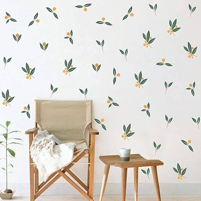 The botanical decals on a wall behind a chair and stool