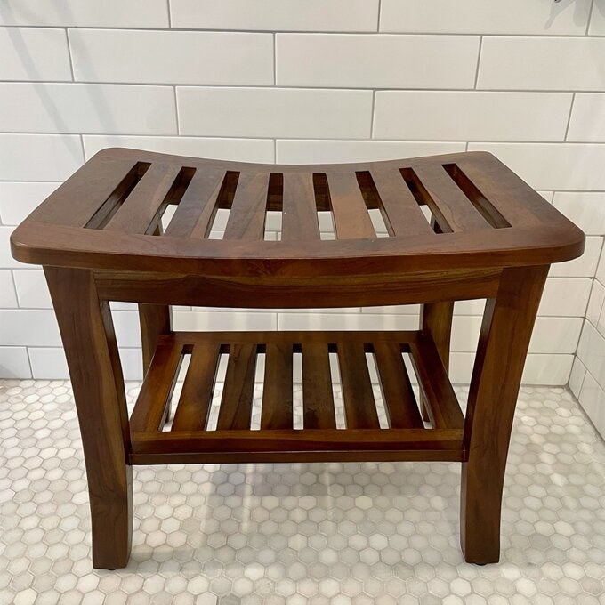 a reviewer photo of the the teak shower bench in a shower