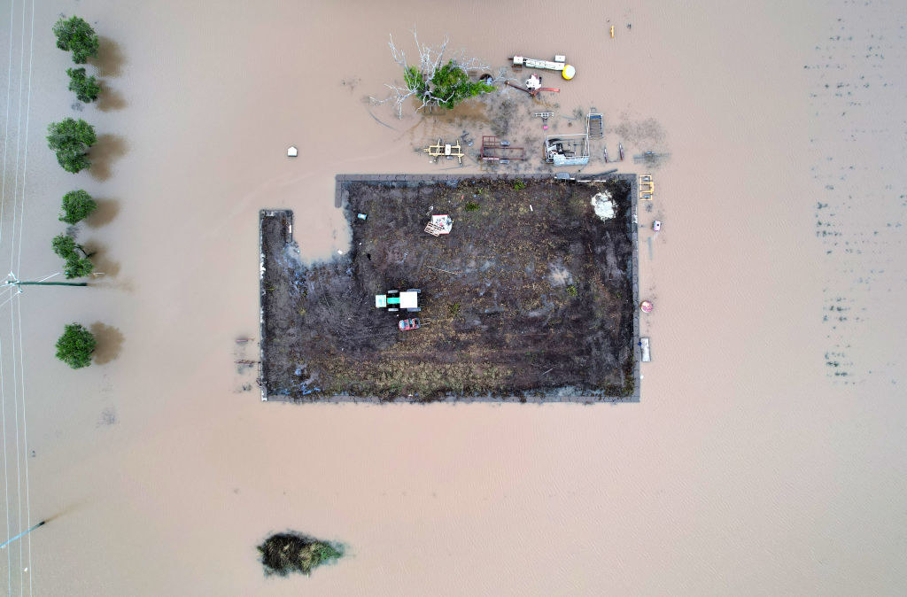 A tractor rests on a small paddock surrounded by floodwater in Brisbane, Australia.