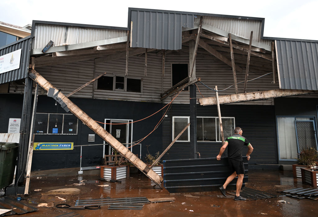A man removes debris from his flood-affected car mechanic business in Lismore, Australia