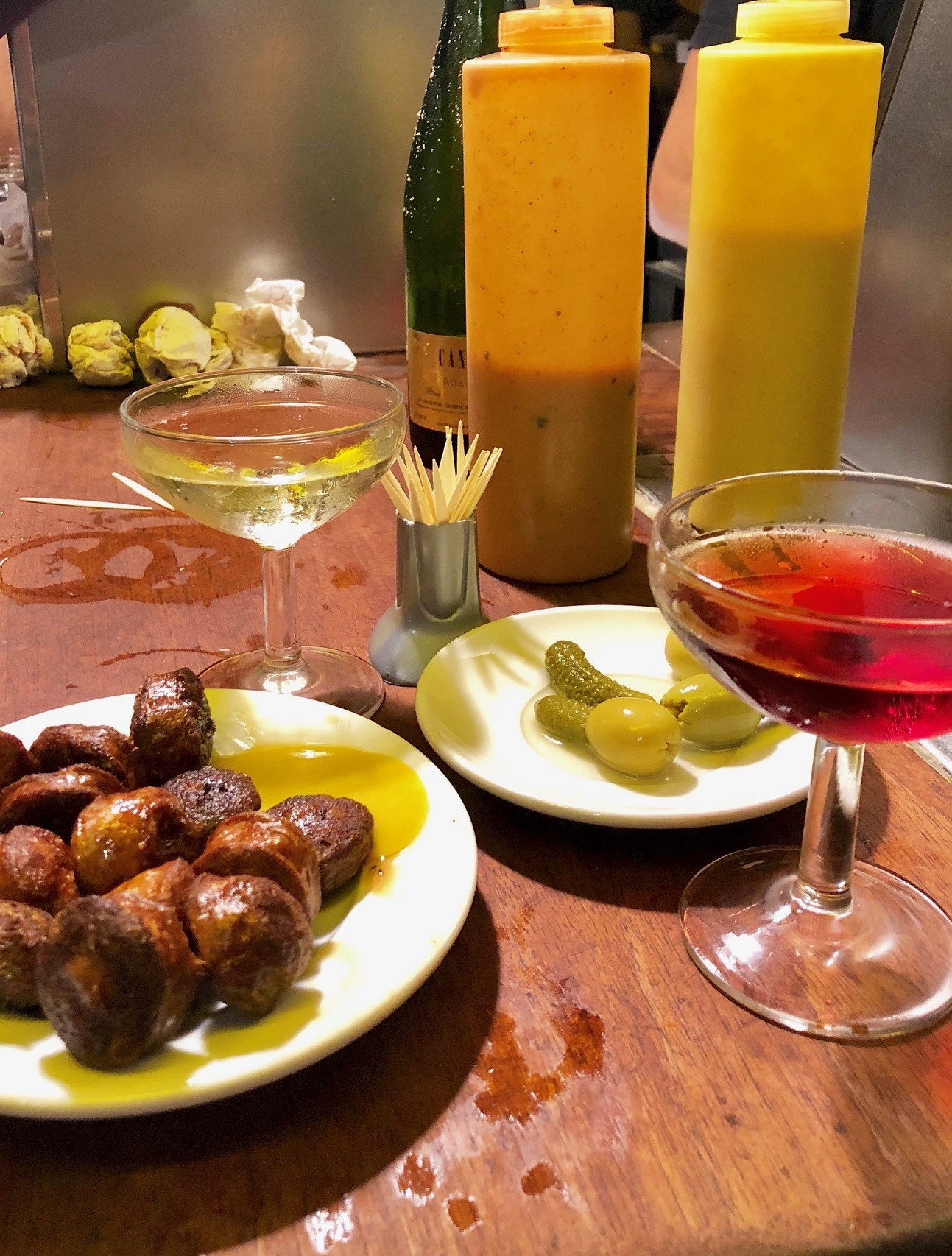 A plate of chorizo, olives, and glasses of sparkling wine