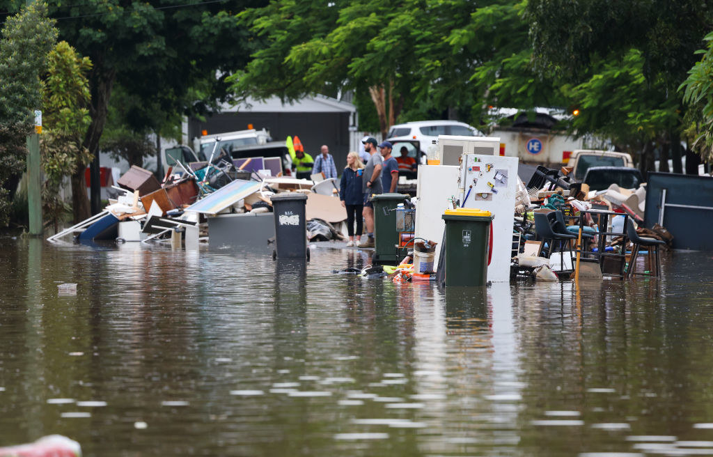 People look on as rubbish is placed at a flooded street in Brisbane, Australia.
