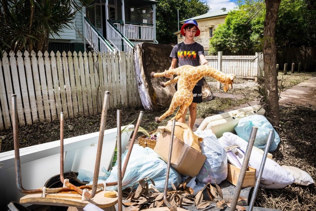 A child throws away a giraffe toy in the flood-damaged suburb of Newmarket in Brisbane