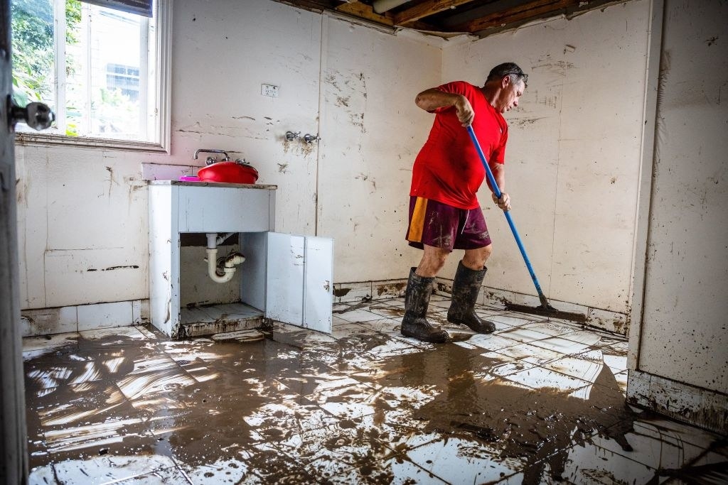 A man clears mud from the lower level of a home following flooding