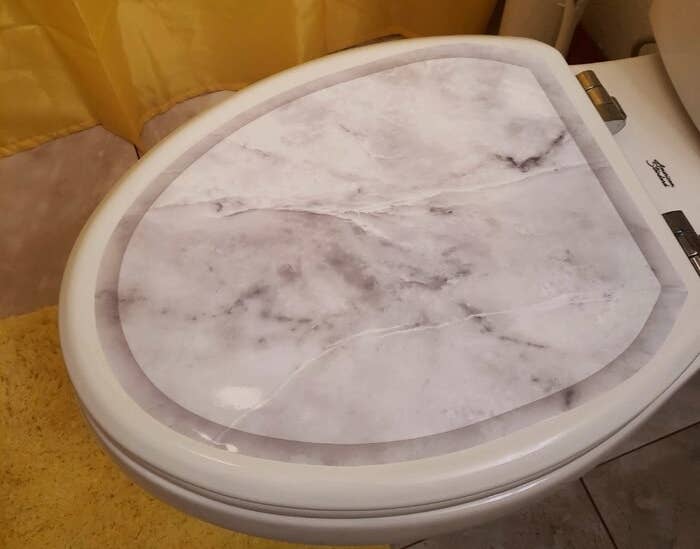 a reviewer photo of the marble toilet seat sticker on a toilet seat