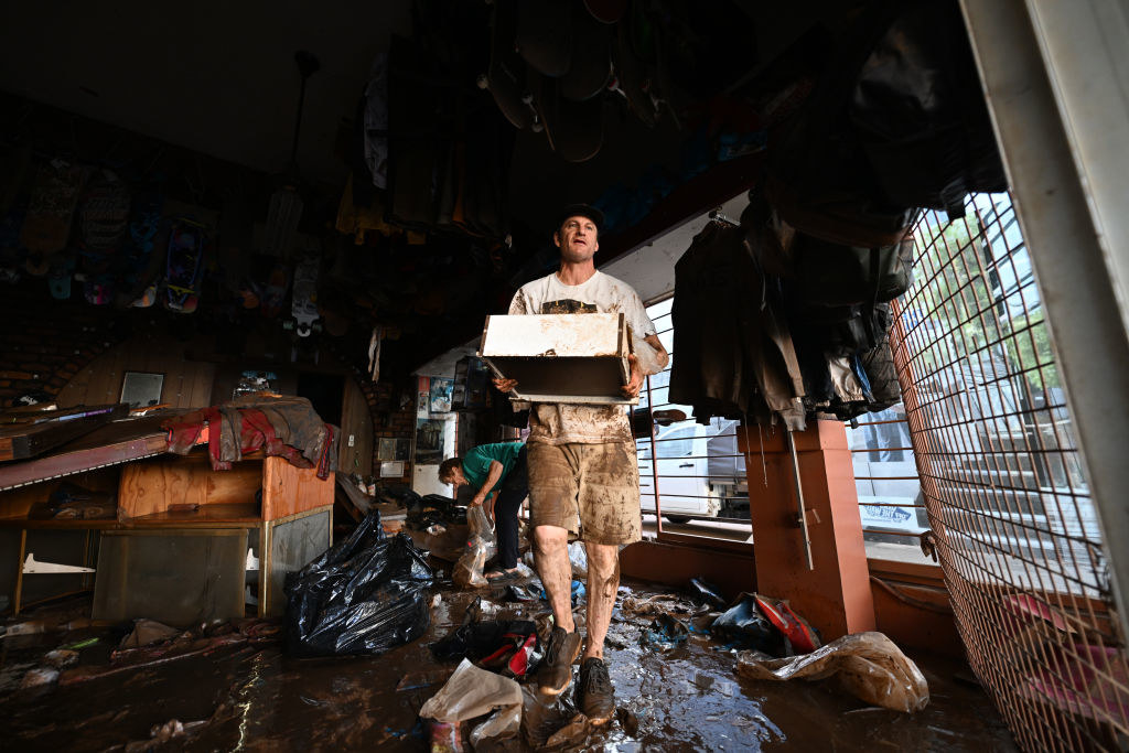 A man throws away flood damaged merchandise from his skate shop
