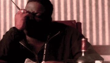 Biggie speaking into a walkie-talkie, while throwing money on a table