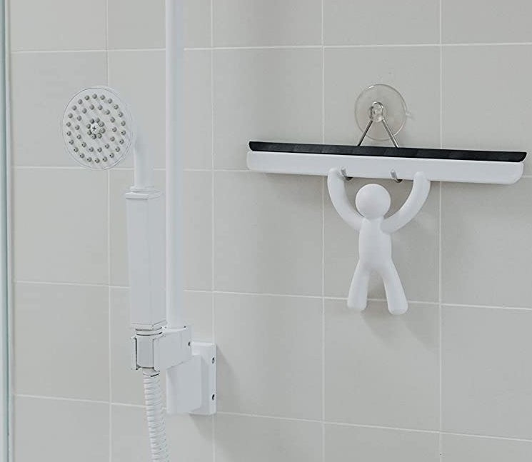 A shower squeegee hanging up in a shower with a suction cup