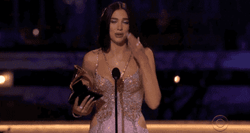 GIF Dua Lipa accepting an award and blowing a kiss