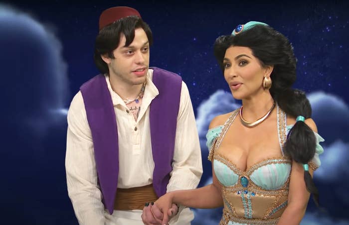 dressed as Jasmine and Aladdin, Kim and Pete hold hands during a SNL sketch