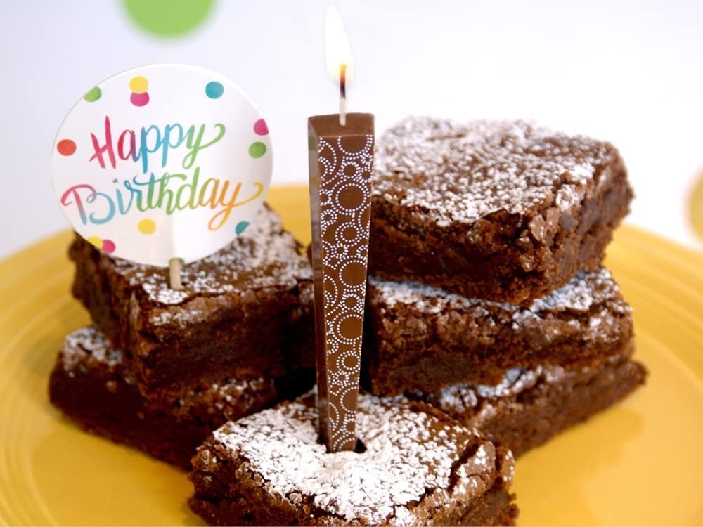 One of the edible candles placed inside a delicious looking brownie that says, &quot;Happy Birthday&quot;