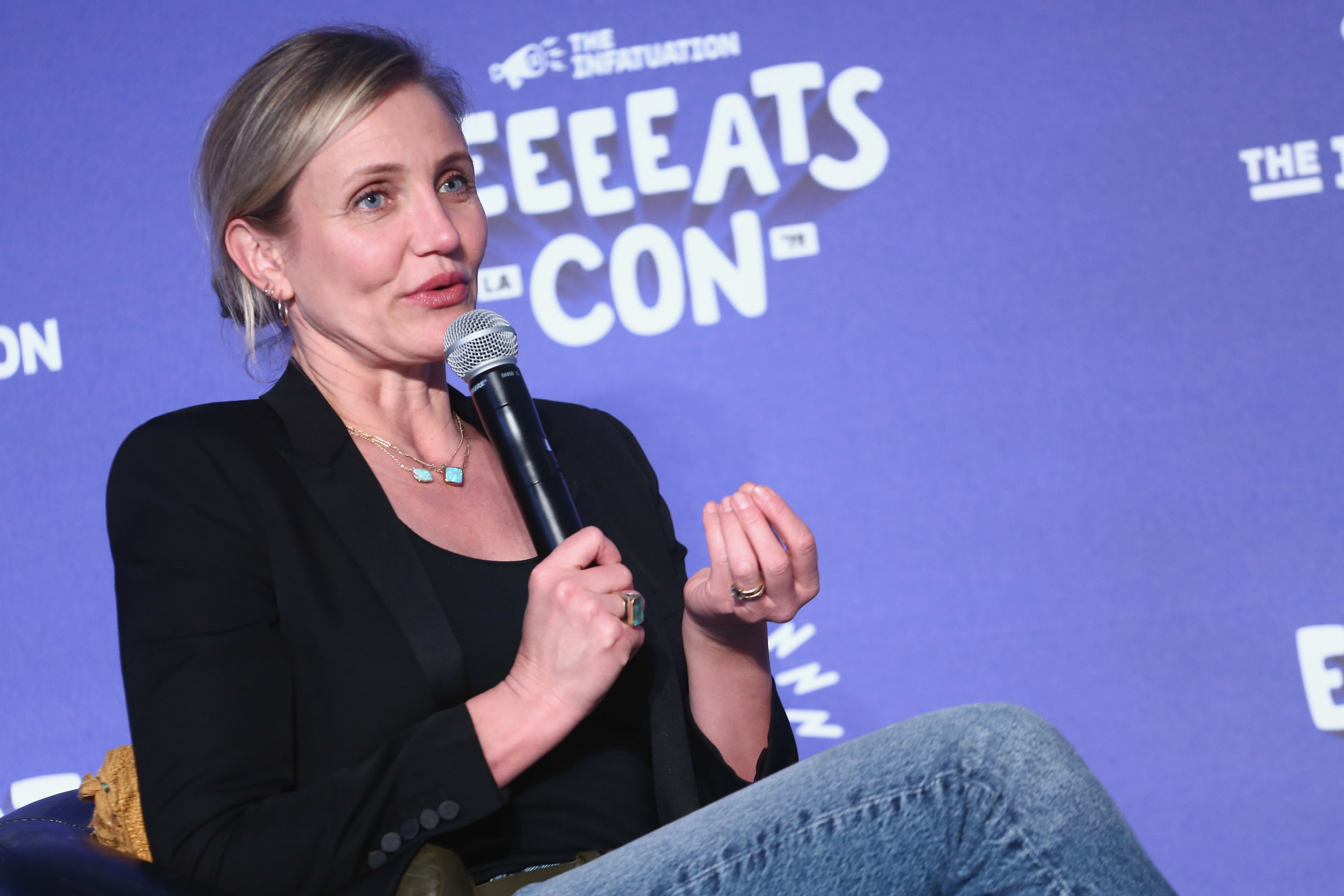 Cameron Diaz holding a mic and speaking on a panel