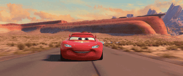 Lightning McQueen driving next to Mater, who is using rockets to go fast
