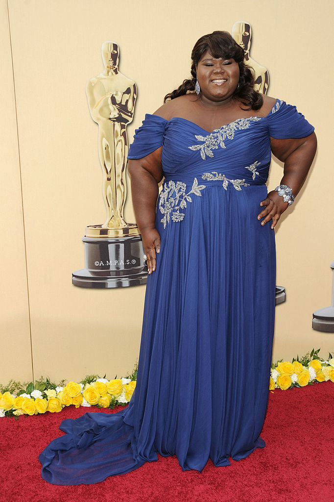 Gabourey wears a goddess-like floor-length dress with off-the-shoulder sleeves, a sweetheart neckline, and silver leaf embroidery